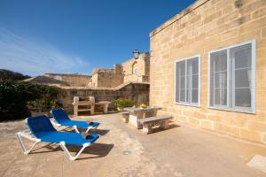 a patio with two chairs and a table and a building at Ghar Ilma IV Holiday Home in Santa Luċija