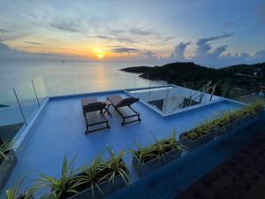 a house with two chairs and a table on a balcony with the sunset at The Beach Residence in Koh Samui