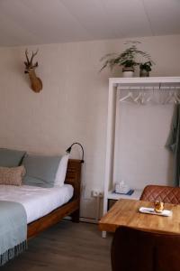 a bedroom with a bed and a table with a deer head on the wall at House Rhodopi in Maldegem