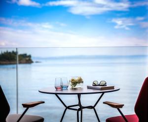 a table with two glasses and a book on it at Boutique & Design Hotel Navis - Small Luxury Hotels of the World in Opatija