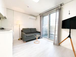 - un salon avec un canapé et une grande fenêtre dans l'établissement W Premium Guesthouse Incheon airport, à Incheon