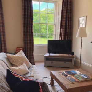 a living room with a couch and a television at Meldon Cottage in Morpeth, Northumberland in Morpeth