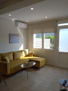 a living room with a yellow couch and two windows at Oasis Apartments in Áyios Andréas
