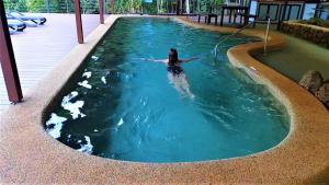 Eine Frau liegt im Wasser in einem Pool. in der Unterkunft Chambers Wildlife Rainforest Lodges in Lake Eacham