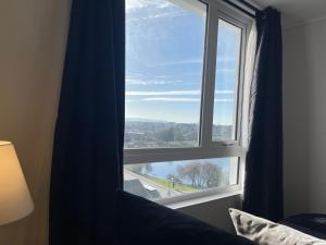 a window in a bedroom with a blue curtain at Loft vista laguna oriente in Concepción