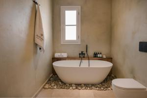 a bathroom with a white tub and a toilet at Uberina - Olea Di Assos Villas in Asos +45 photos