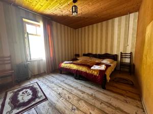 a bedroom with a bed with a wooden floor and a window at Guesthouse Angelina in Ushguli