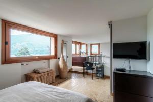 een slaapkamer met een groot raam en een televisie bij Sun Luxury Apartment with Swimming Pool - Blevio in Blevio