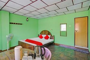 1 dormitorio con paredes verdes y 1 cama con almohadas rojas en Flagship Green Fort Thekkady, en Thekkady