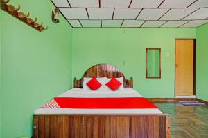 卡迪的住宿－Flagship Green Fort Thekkady，一间卧室配有一张带红色枕头的大床