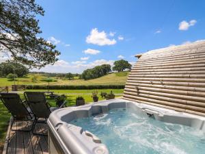 a hot tub on a deck with a view of a yard at Pine Lodge in Llangadog