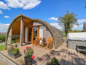 a small wooden cabin with a deck and a grill at Pine Lodge in Llangadog