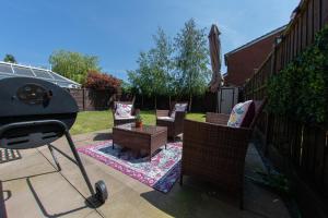 a patio with chairs and an umbrella and a grill at Styche View, beautiful 4 bedroom home available in Market Drayton