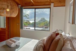 1 dormitorio con cama y ventana grande en HEXAGON BEACH HOUSE Binalong Bay of Fires Views en Binalong Bay