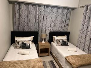 a bedroom with two beds and a side table at Bee's Central Hideout in Windhoek