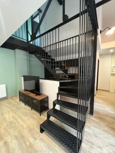 a black spiral staircase in a room with a table at La Manufacture du Sable in Berck-sur-Mer
