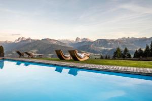 a swimming pool with a view of mountains at Granpanorama Wellnesshotel Sambergerhof Superior in Villandro