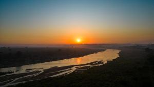 a sunset over a river with the sun setting in the background at Buckler's Africa Lodge Kruger Park in Komatipoort