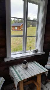 a window with a wooden bench in front of a table with a box on it at Leppälän vanhatupa rantasaunalla in Utsjoki