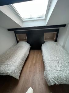 two beds in a room with a window at La Manufacture du Sable in Berck-sur-Mer