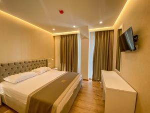 ein Hotelzimmer mit einem Bett und einem Flachbild-TV in der Unterkunft Red Hill Hotel in Tirana