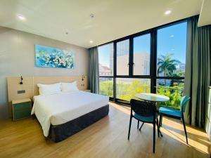 Una habitación de hotel con una cama, una mesa y sillas. en NAM Hotel & Residences, en Da Nang