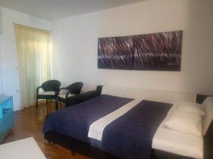 a hotel room with a bed and two chairs at Apartmani Labud in Sukošan