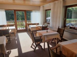 um restaurante com mesas, cadeiras e janelas em Pension-Gästehaus Waldhof em Winterberg