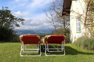 duas cadeiras vermelhas sentadas na relva ao lado de uma casa em Monika am Masenberg em Vorau