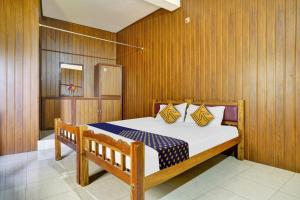 1 dormitorio con 1 cama con paneles de madera en SPOT ON Aiwa Residency en Muttam