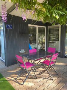 uma mesa preta e cadeiras cor-de-rosa num deque em La Paillotte - 6 personnes em Pommeret