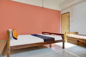 1 dormitorio con cama y pared de color naranja en SPOT ON Aiwa Residency en Muttam