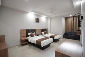 een hotelkamer met 2 bedden en een bank bij Hotel Krishna Inn in Jaipur