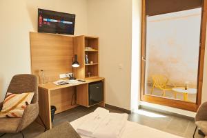 Habitación con escritorio y TV en la pared. en Hotel Casa Palacio Pereros en Cáceres