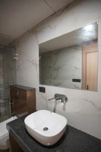een badkamer met een witte wastafel en een spiegel bij Hotel Krishna Inn in Jaipur