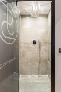 La salle de bains est pourvue d'une douche avec une porte en verre. dans l'établissement Urban suites- HELEXPO, à Thessalonique
