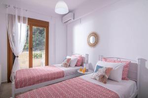 Duas camas num quarto branco com uma janela em Beachfront Orange apt-Ligaria Beach em Ligaria