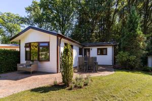 een klein wit huis met een patio in een tuin bij Huize Bosrijk aan het water in Kootwijk