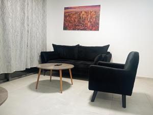 a living room with a black couch and a table at Agamim Park Residence in Ashkelon