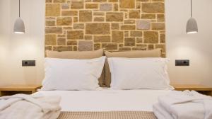 a bed with white pillows and a brick wall at Aurelia Luxury Apartments in Agios Ioannis Kaspaka