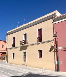 a building with red windows on a street at Su Zampillu Boutique Rooms Teulada in Teulada