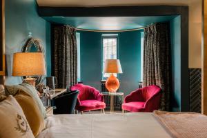 a bedroom with a bed and two pink chairs at The George in Hathersage