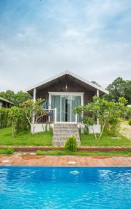 a house with a swimming pool in front of a house at Kanasu The Resort - Cottages & Farm House in Udupi