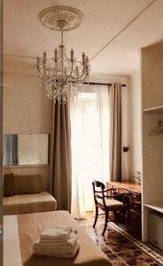 una camera da letto con lampadario pendente, scrivania e sedia di Su Zampillu Boutique Rooms Teulada a Teulada