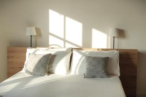 uma cama com lençóis brancos e almofadas num quarto em La Crosona em Colà di Lazise