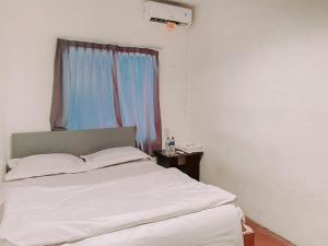 Cama blanca en habitación con ventana en Penginapan Steady Mitra RedDoorz en Pematangsiantar