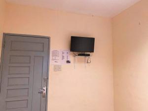 une télévision sur un mur à côté d'une porte dans l'établissement Penginapan Steady Mitra RedDoorz, à Pematang Siantar