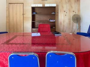 una mesa de cristal con una silla roja y una roja en Penginapan Steady Mitra RedDoorz en Pematangsiantar