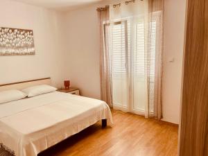 a white bedroom with a bed and a window at Villa Roseal in Povljana