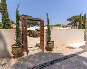 an open door with two potted plants on a wall at Hôtel L'Escalet in Ramatuelle